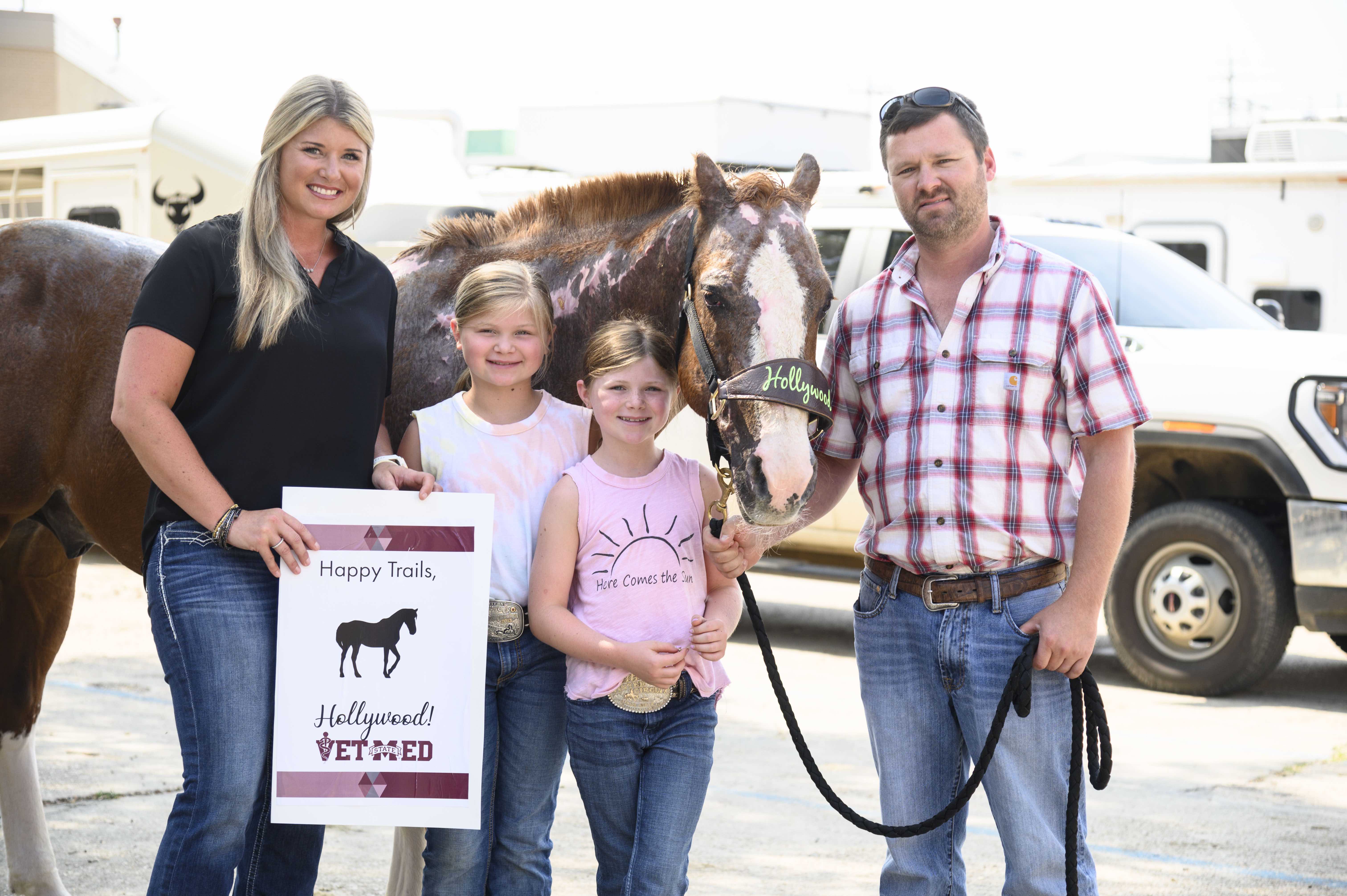 A family poses with their horse