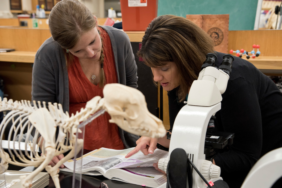 Dr. Alicia Olivier shows a student something in a text book.