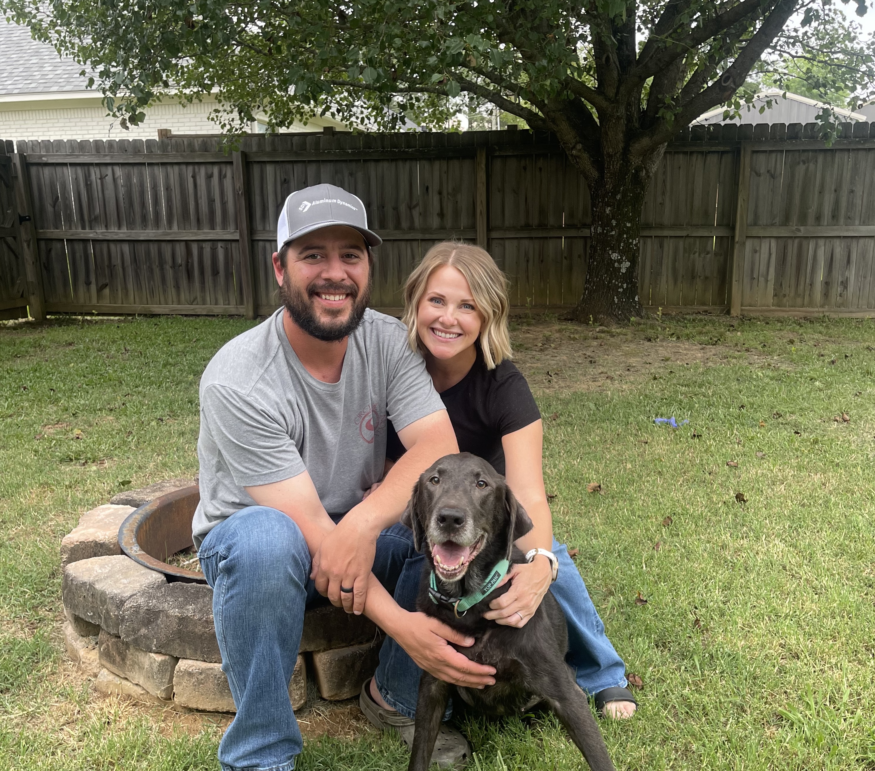 Two people hug a dog